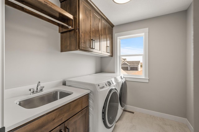 laundry room featuring sink, washer and clothes dryer, and cabinets