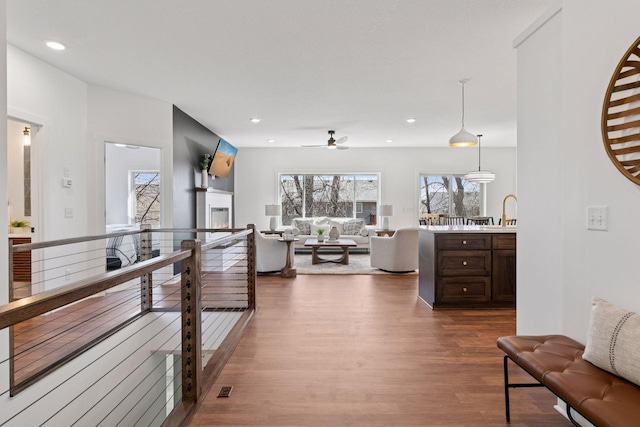 living room featuring recessed lighting, dark wood-type flooring, and a glass covered fireplace