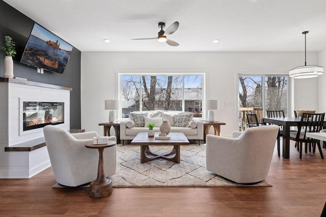 living room featuring a wealth of natural light, wood finished floors, a glass covered fireplace, and recessed lighting