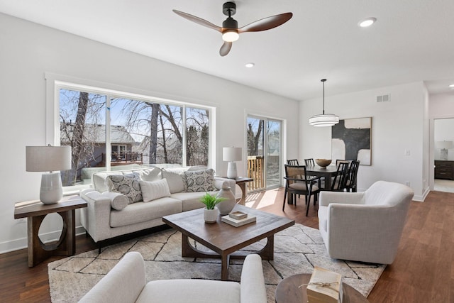 living area featuring a ceiling fan, wood finished floors, visible vents, baseboards, and recessed lighting