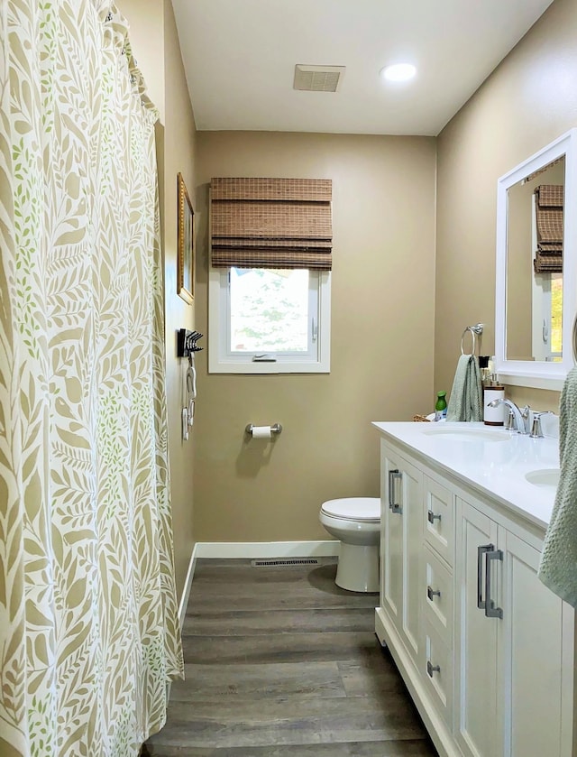 bathroom with wood-type flooring, vanity, and toilet