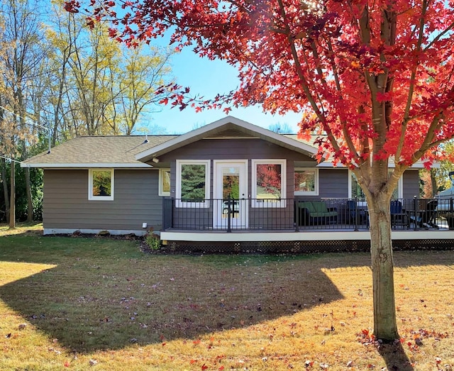 back of property featuring a yard, roof with shingles, and a wooden deck