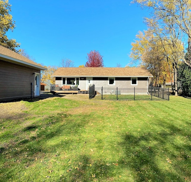 back of property with a deck, a yard, and fence