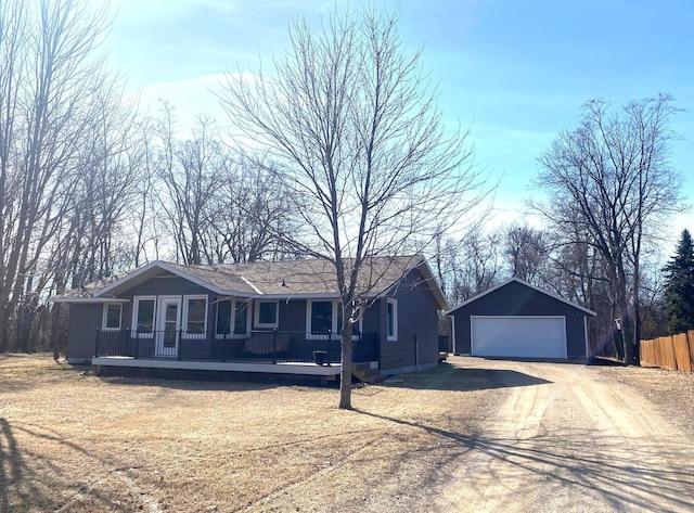 single story home featuring an outbuilding, a detached garage, a deck, and fence