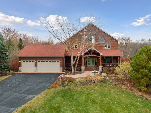 view of front of property with a porch, a front lawn, and a garage