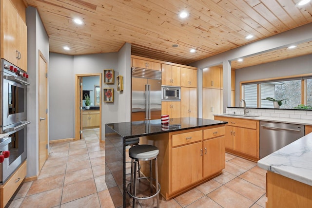 kitchen featuring built in appliances, sink, a center island, and stone counters