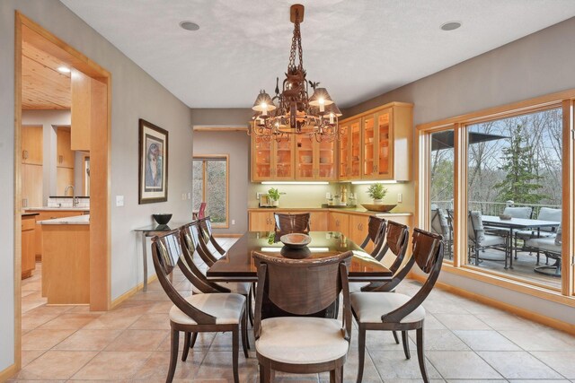 dining room with light tile patterned floors, an inviting chandelier, and sink