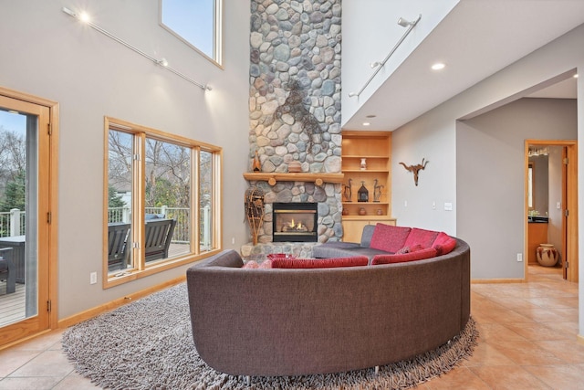 tiled living room with a stone fireplace, built in features, and a high ceiling