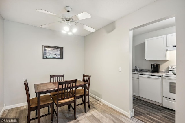 dining space featuring ceiling fan, sink, and light wood-type flooring