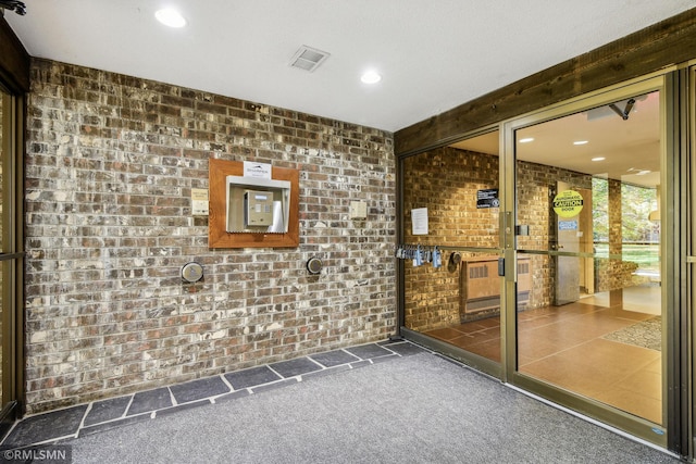 interior space featuring brick wall and dark carpet