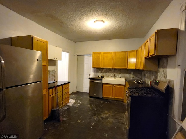 kitchen with appliances with stainless steel finishes, a textured ceiling, sink, and backsplash