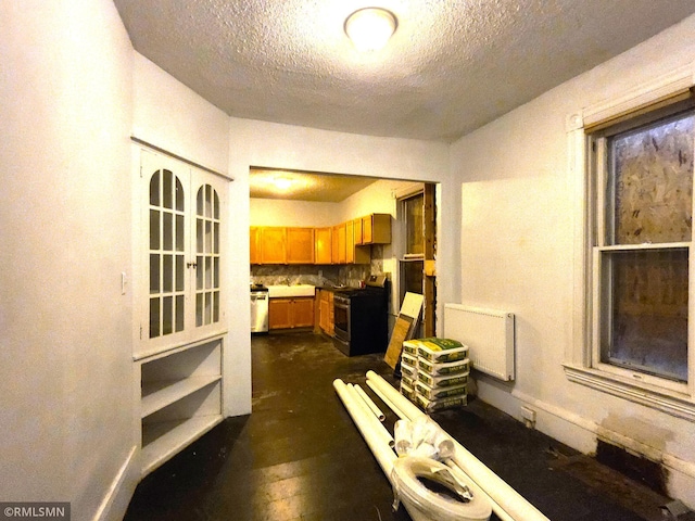 kitchen featuring appliances with stainless steel finishes, a textured ceiling, radiator heating unit, dark hardwood / wood-style flooring, and decorative backsplash