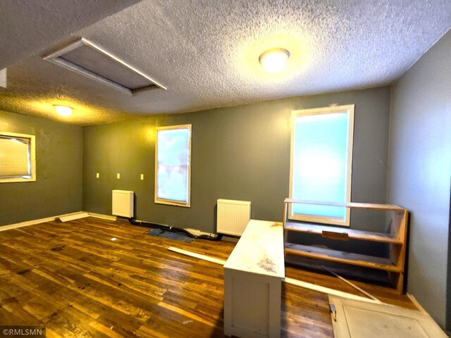 interior space with radiator heating unit, a textured ceiling, and dark wood-type flooring