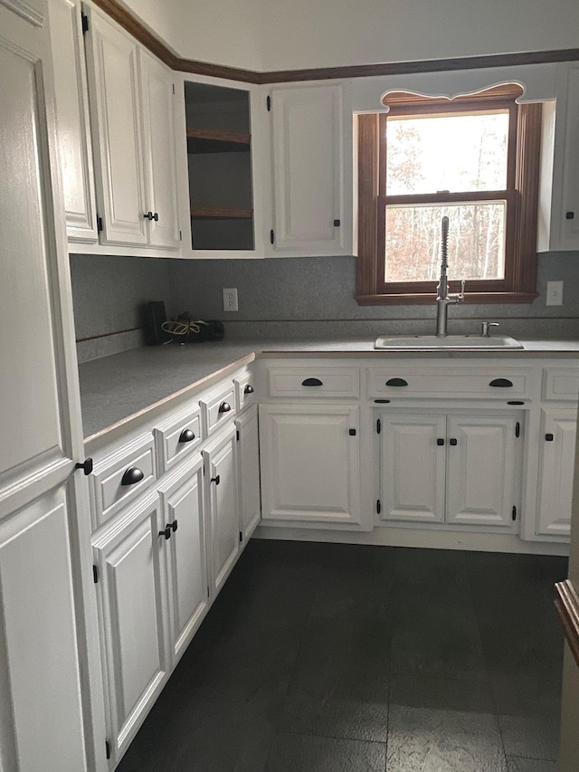 kitchen with sink, dark tile patterned floors, and white cabinets