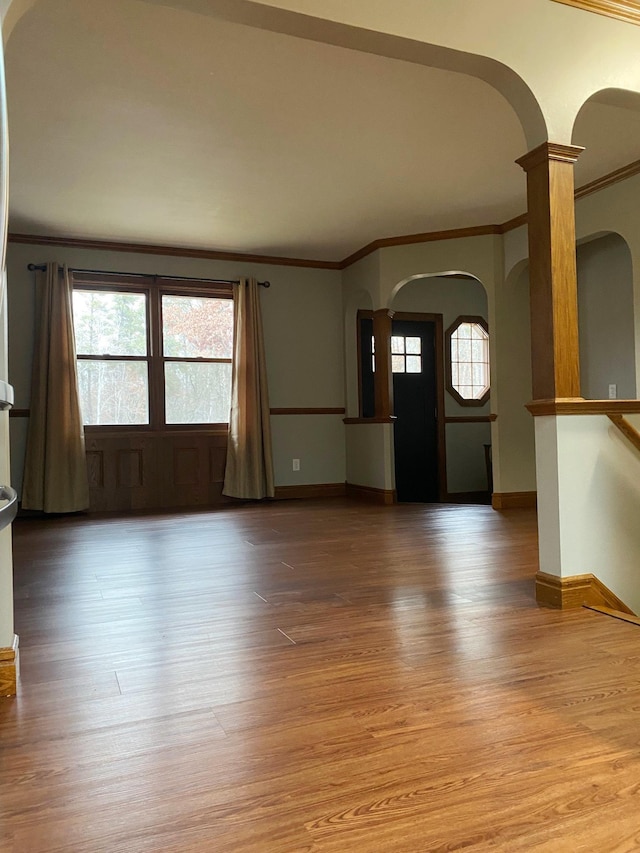 entrance foyer with crown molding, hardwood / wood-style floors, ornate columns, and a wealth of natural light