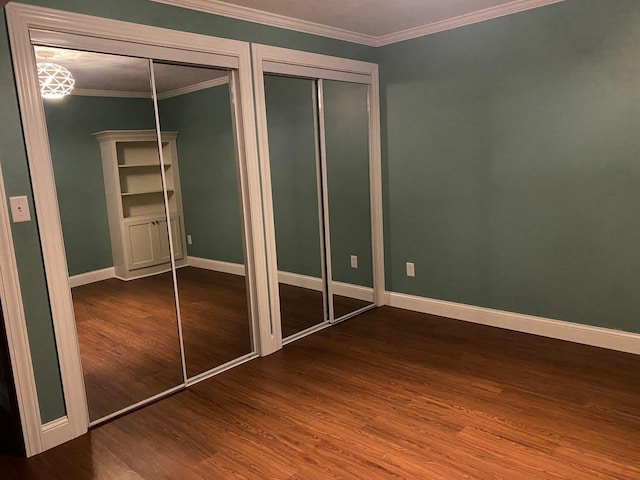 unfurnished bedroom with multiple closets, hardwood / wood-style floors, and crown molding