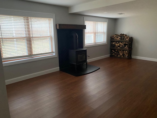 unfurnished living room featuring a wood stove and dark hardwood / wood-style flooring