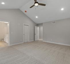 unfurnished bedroom featuring ceiling fan, light colored carpet, lofted ceiling, and ensuite bath