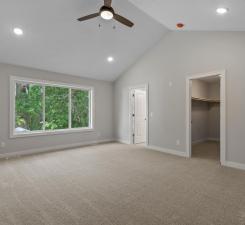 unfurnished bedroom with light carpet, vaulted ceiling, ceiling fan, a spacious closet, and a closet