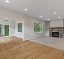 unfurnished living room with a stone fireplace and light hardwood / wood-style flooring