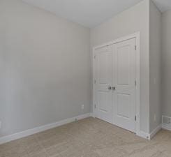 unfurnished bedroom with light colored carpet and a closet