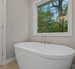 bathroom with tile patterned floors, plenty of natural light, and a bathtub