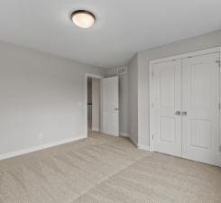 unfurnished bedroom with light colored carpet and a closet