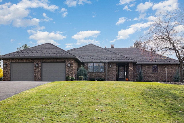 single story home featuring a front lawn, driveway, an attached garage, brick siding, and a chimney