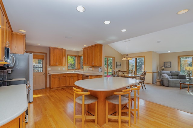 kitchen featuring a breakfast bar area, a sink, light countertops, vaulted ceiling, and open floor plan