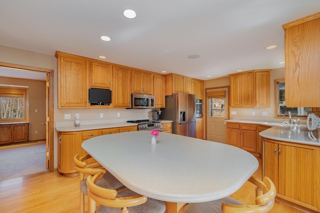 kitchen with light wood-type flooring, light countertops, recessed lighting, stainless steel appliances, and a sink