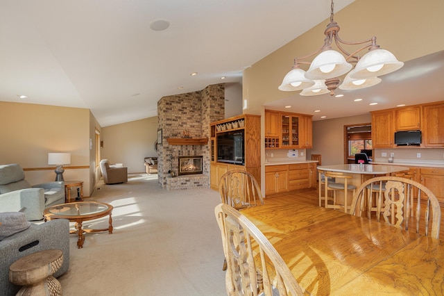 dining space with an inviting chandelier, lofted ceiling, recessed lighting, light carpet, and a brick fireplace