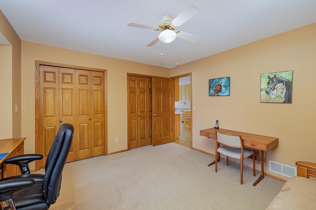 home office with visible vents, baseboards, light colored carpet, and a ceiling fan