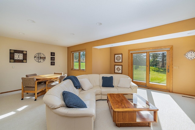 living room featuring a wealth of natural light, baseboards, and light colored carpet