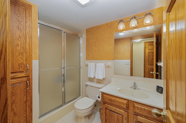 full bath featuring vanity, a shower with shower door, tile walls, toilet, and tile patterned floors