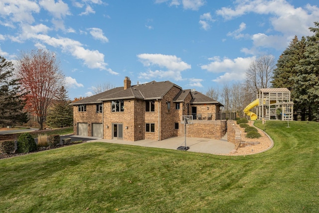 back of property with a chimney, a patio, an attached garage, and a yard