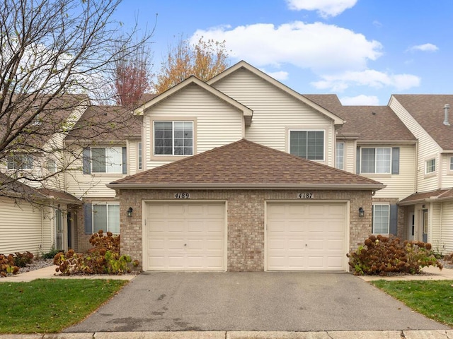 view of property with driveway, brick siding, roof with shingles, and an attached garage