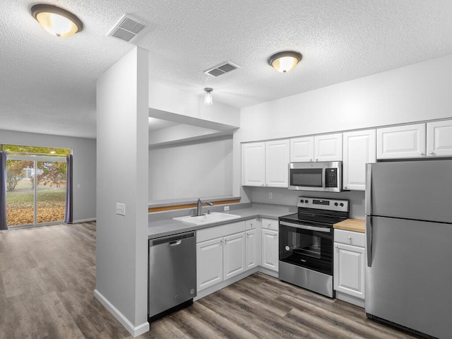 kitchen with stainless steel appliances, white cabinets, a sink, and visible vents