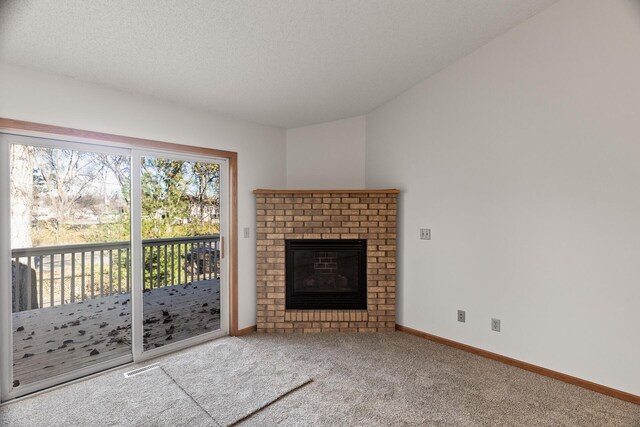 unfurnished living room with carpet flooring, a brick fireplace, and a textured ceiling