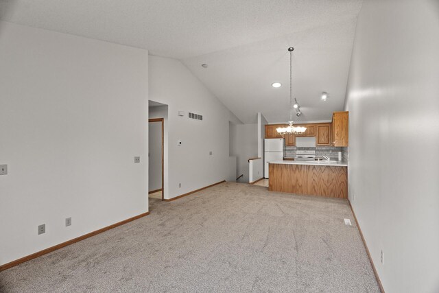 unfurnished living room with a textured ceiling, light colored carpet, lofted ceiling, and a chandelier