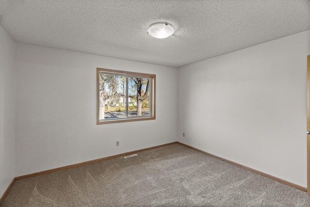 carpeted empty room with a textured ceiling