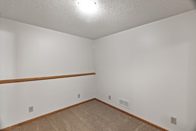 carpeted empty room with a textured ceiling