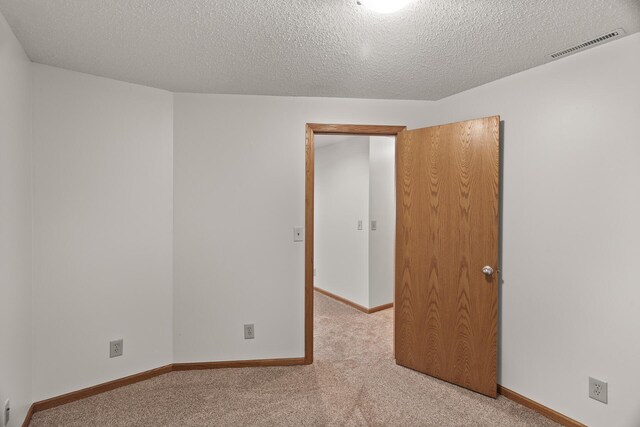 unfurnished room featuring light carpet and a textured ceiling