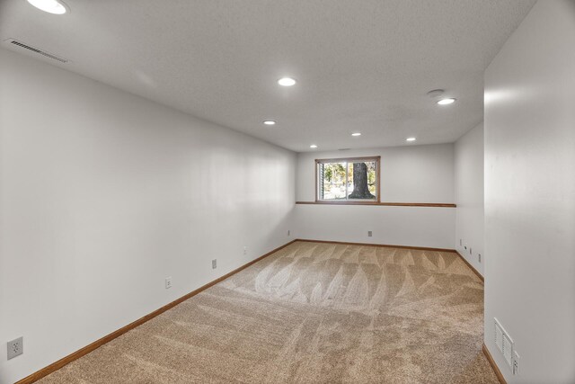 spare room featuring a textured ceiling and light colored carpet