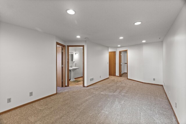 unfurnished room with light colored carpet and sink