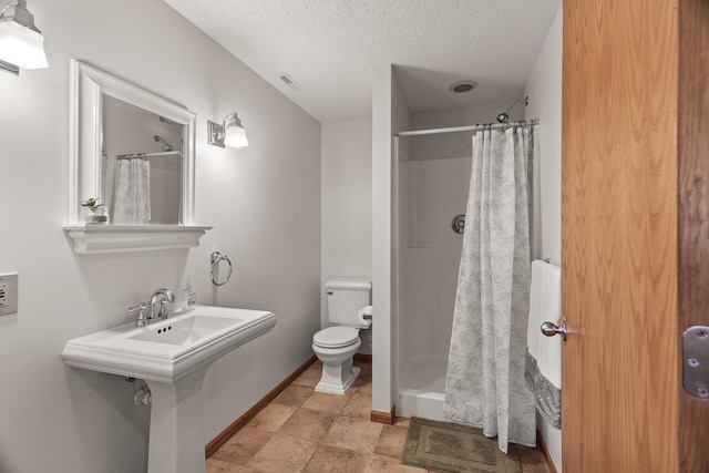 bathroom featuring toilet, a textured ceiling, and curtained shower