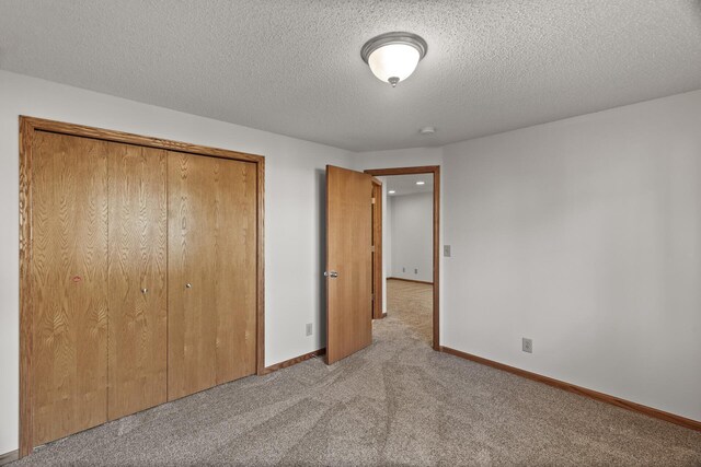 unfurnished bedroom with light colored carpet, a textured ceiling, and a closet