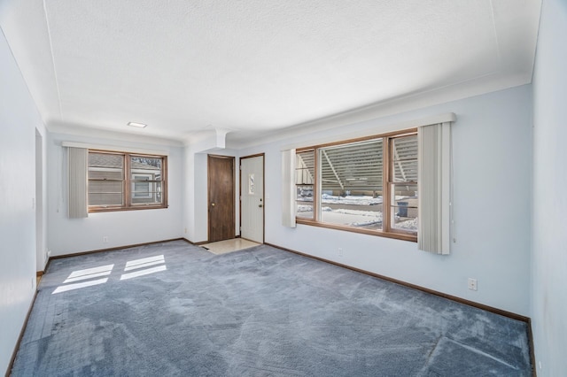 empty room featuring carpet, baseboards, and a textured ceiling