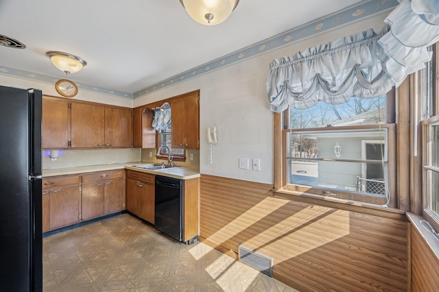 kitchen featuring visible vents, light countertops, brown cabinets, black appliances, and a sink