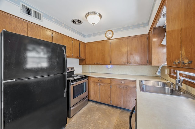 kitchen featuring visible vents, a sink, stainless steel electric stove, freestanding refrigerator, and light countertops