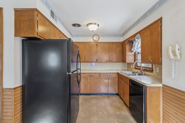 kitchen with visible vents, light floors, brown cabinetry, black appliances, and a sink